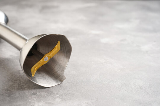 Immersion hand blender on a gray table, space for text. Close-up.