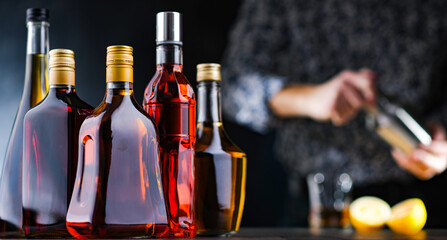 Bottles of assorted alcoholic beverages and bartender - obrazy, fototapety, plakaty