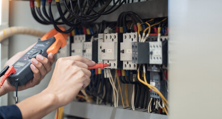Electrician engineer work tester measuring voltage and current of power electric line in electical cabinet control , concept check the operation of the electrical system .