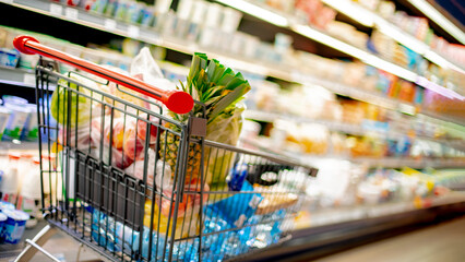 A shopping cart with grocery products in a supermarket