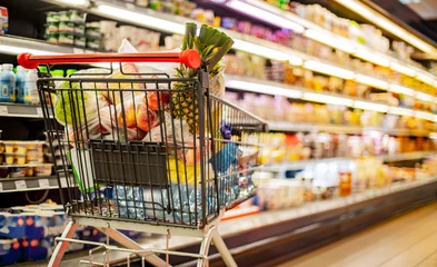 Foto op Plexiglas A shopping cart with grocery products in a supermarket © monticellllo