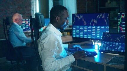 African stockbroker is calculating stock rates at his desk. Businessman trader, broker concept. - Powered by Adobe