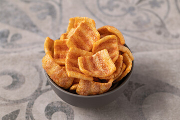 bacon snacks in a ceramic bowl, appetizer, on a gray background with a pattern, close-up