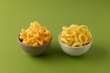 snacks, onion rings, cheese snacks, snack set, on a green background in ceramic bowls