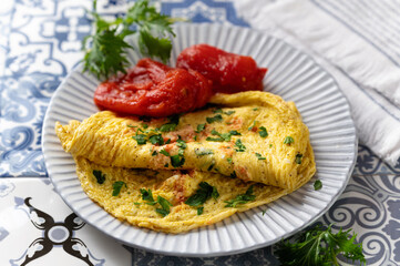 omelet, scrambled eggs cracked with flour and milk with tomatoes and herbs, traditional breakfast