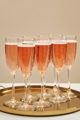 graceful glasses with rose sparkling wine on a golden tray