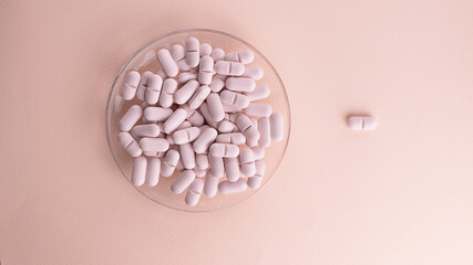 Pills on plate pink background and one on background. Creative concept for Valentine's Day or Pharmacy, Dietary Supplement and Medicines.