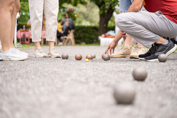 Petanque players measure distance in bocce metal ball french game in city park on summer sunset