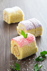 Various flavour swiss roll cake on wooden table.