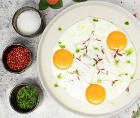 Breakfast. fried eggs from three eggs are sprinkled with grass on a light plate. next to seasonings and spices. High quality photo
