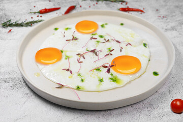 Breakfast. fried eggs from three eggs are sprinkled with grass on a light plate. . High quality photo