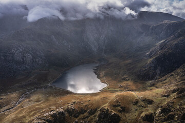 Aerial view of flying drone Epic dramatic Autumn landscape image of Llyn Idwal in Devil's Kitchen in Snowdonia National Park with gorgeous light