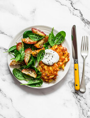 Potato latkes with baked apples, spinach salad on a light background, top view