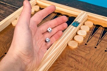 The boy throws two dice on the backgammon board.
