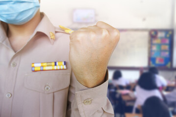 male teacher showing fist, wearing Thai servant uniform,classroom as background, strong and...