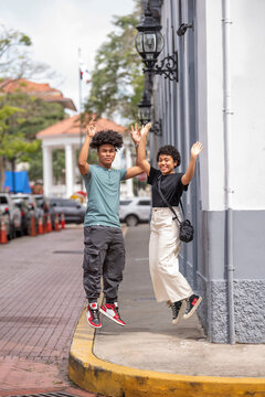 Latin couple waving hands and jumping on sidewalk, Panama City