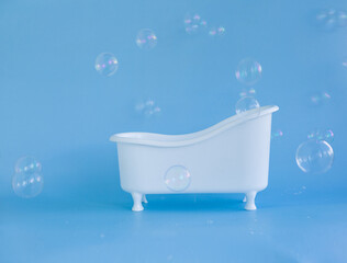 Empty white bathtub toy on a blue background and soap bubbles foam