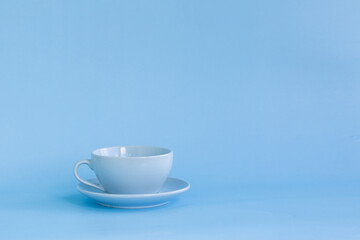 Blue cup and saucer on a blue background side view.