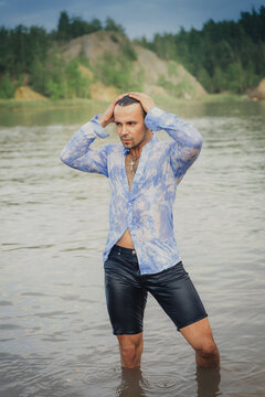 A Man With Dark Long Hair Emerges From The Water In A Wet Shirt.