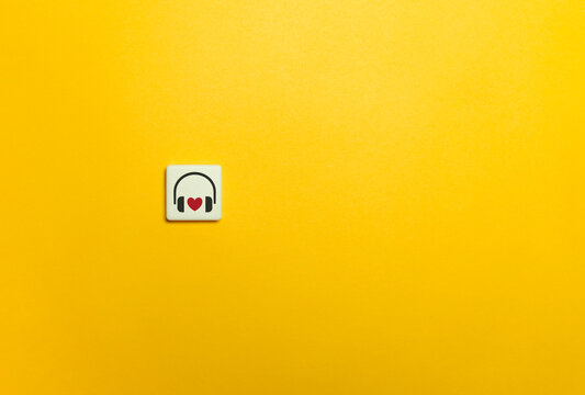 Headphones and Heart Symbol on Yellow Background. Favourite Song and Music Concept.