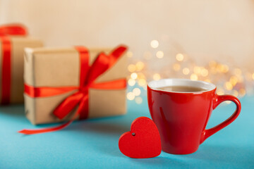 Gift box, red heart and red cup of tea on a blue background. Valentine's Day gift. Holidays and love concept.