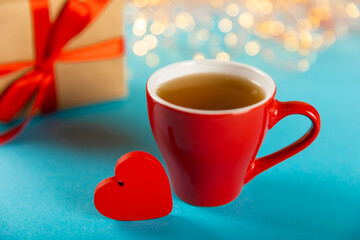 Gift box, red heart and red cup of tea on a blue background. Valentine's Day gift. Holidays and love concept.