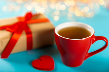 Gift box, red heart and red cup of tea on a blue background. Valentine's Day gift. Holidays and love concept.
