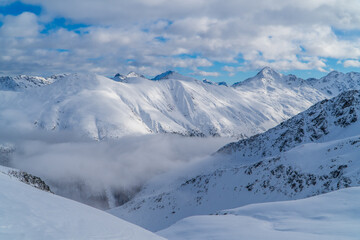 Fototapeta na wymiar Amazing alpine panoramic view in Livigno, Italy with clouds below snowy peaks