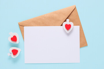 Valentine's day concept. Craft envelopes, white blank sheet of paper and wooden clips hearts on a...