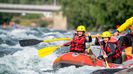 Two girls enjoying themself with river rafting water sports. Smiles, recreation and happiness concept. Removed logos. - obrazy, fototapety, plakaty