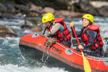 Two girls enjoying themself with river rafting water sports. Smiles, recreation and happiness concept. Removed logos. - obrazy, fototapety, plakaty