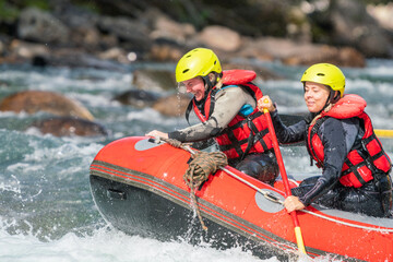 Two girls enjoying themself with river rafting water sports. Smiles, recreation and happiness concept. Removed logos.