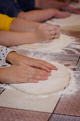 Obraz na płótnie Canvas Childrens hands and flour, making dough for pizza and pies 