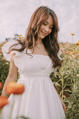 Fototapeta na wymiar Portrait of thai young woman enjoying in blooming flower field