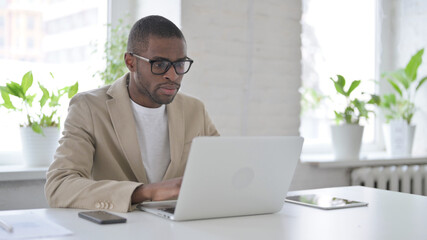 African Man Working on Laptop in Office