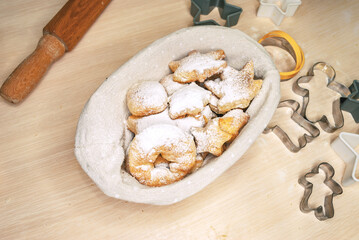 Fresh homemade cookies in a basket sprinkled with powdered sugar on the table. Tableware for making cookies.