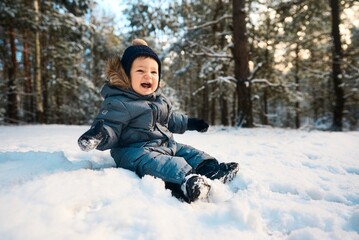 A little boy in the snow. Happy child walking through winter forest
