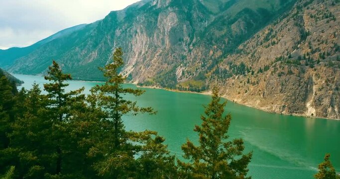 Aerial Scenic Shot Of River Flowing By Mountains, Drone Flying Forward Over Green Trees - British Columbia, Canada