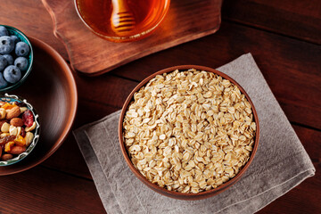 Oatmeal flakes, blueberries, honey and assorted nuts on a wooden background. Cereal and various delicious ingredients for breakfast. Top view