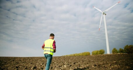 The engineer goes to the windmills power turbines with the tablet in his hand - Powered by Adobe
