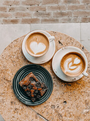 hot coffee latte art in white cup and chocolate brownie on white plate served in vintage wood tray on rustic wood table top view.