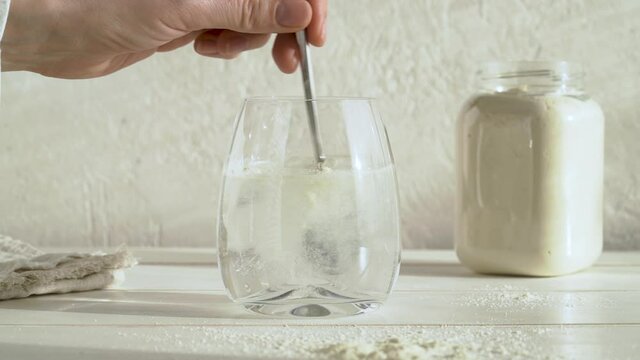 Putting a teaspoon of whey protein powder into a glass of water and stirring it, slow motion