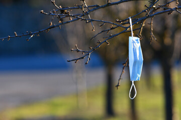 mask used and abandoned in nature, hanging from a tree branch. Used protective masks abandoned...