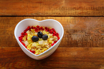 Puff salad with pineapple in a salad bowl decorated with pomegranate on the table.