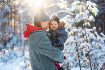 Young mother and her baby playing in the snowy forest. Young mother carrying her baby in the forest on a very snowy day.