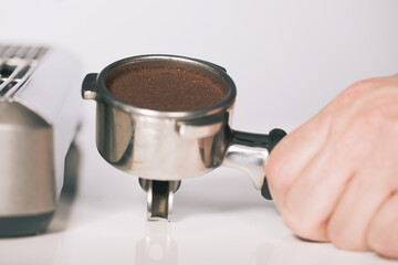 Pressing ground coffee in handle for extracting in espresso machine