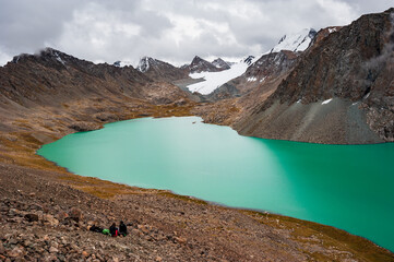 Group of trekker backpackers sitting relaxing at bank of Beautiful landscape of turquoise Ala-Kul...
