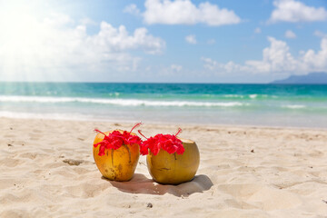 Two coconut cocktails on white sand beach