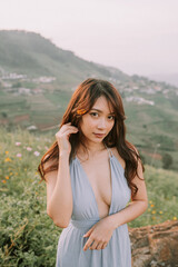 Portrait of thai young woman in blue dress in a flower field in mountains