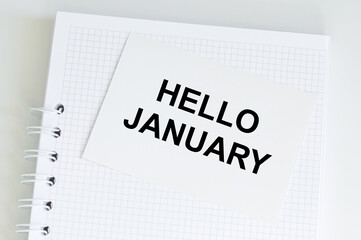 Hello January text on a card on the background of a notebook on the table